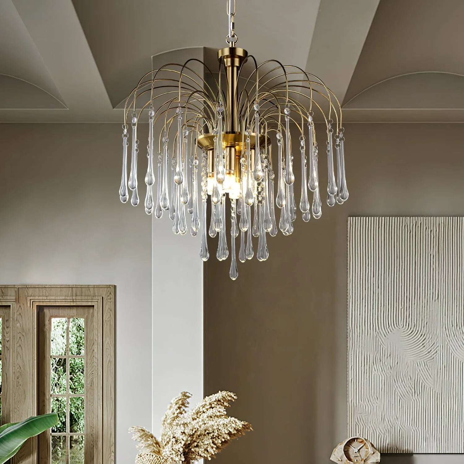 Modern brass chandelier with clear glass teardrop pendants hanging in a stylish living room