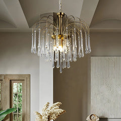Modern brass chandelier with clear glass teardrop pendants hanging in a stylish living room