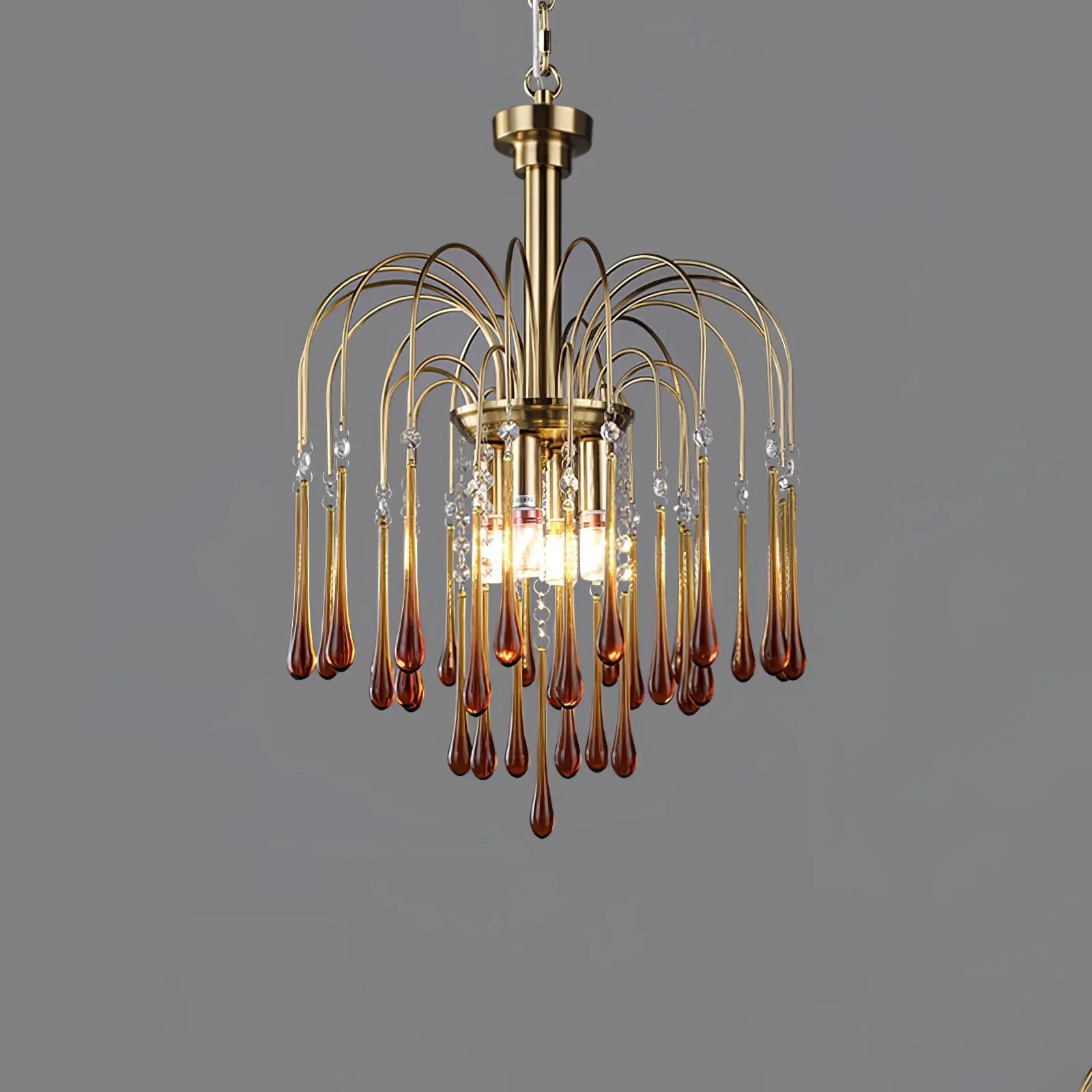 Modern brass chandelier pendant lamp with amber glass droplets and clear crystal accents on gray background
