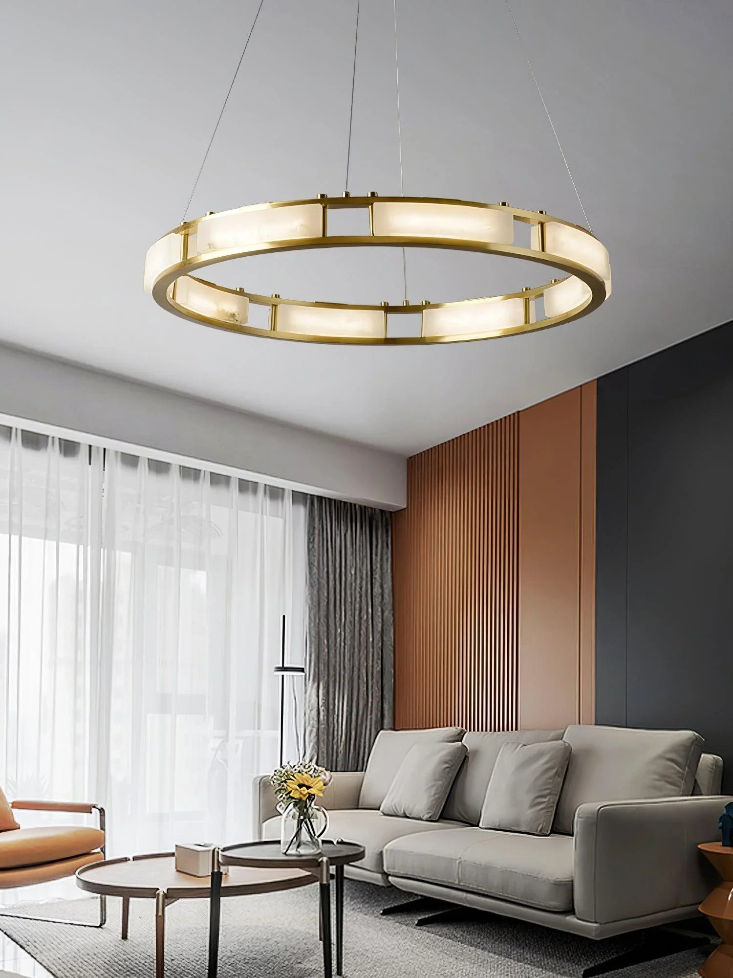 Modern circular brass and alabaster pendant chandelier over gray sofa in stylish living room