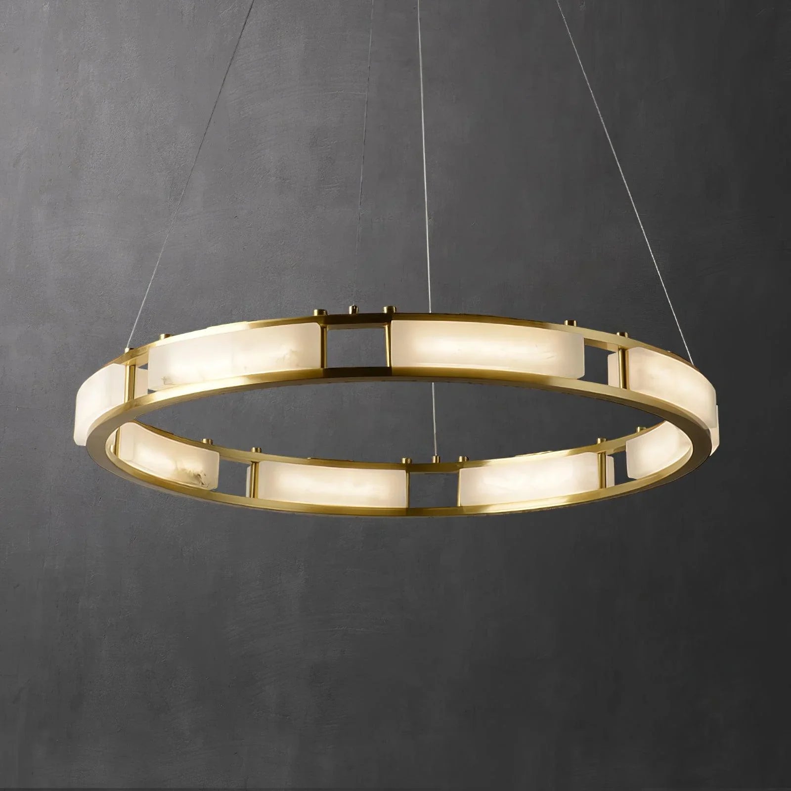 Modern circular chandelier with brass frame and alabaster light panels against dark wall
