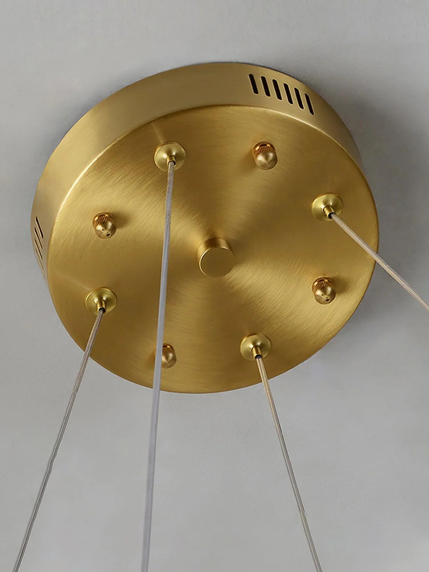 Close-up of brass ceiling canopy with four transparent cords for a modern chandelier lighting fixture