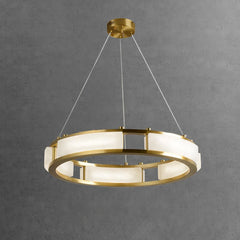 Modern round brass chandelier with white alabaster panels hanging on wires against gray wall