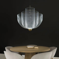 Modern mesh pendant chandelier with chrome body and gold base hanging above round wooden dining table with beige chairs