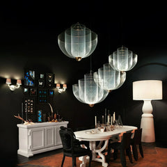 Modern dining room with white table, black chairs, artistic pendant lamps, white sideboard, and large floor lamp