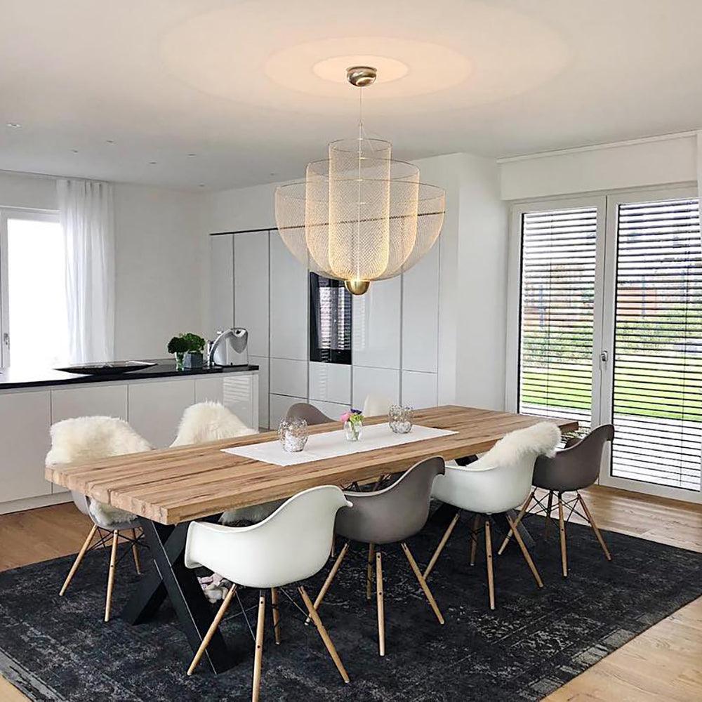 Modern dining room with a wooden table, mixed white and gray chairs, and a gold-based mesh pendant chandelier