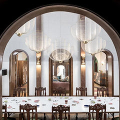 Elegant modern dining room with white table, ornate wooden chairs, and multiple mesh pendant chandeliers