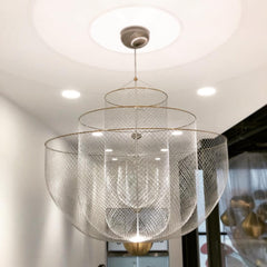 Modern mesh pendant chandelier with chrome body and gold base hanging from ceiling in minimalist room