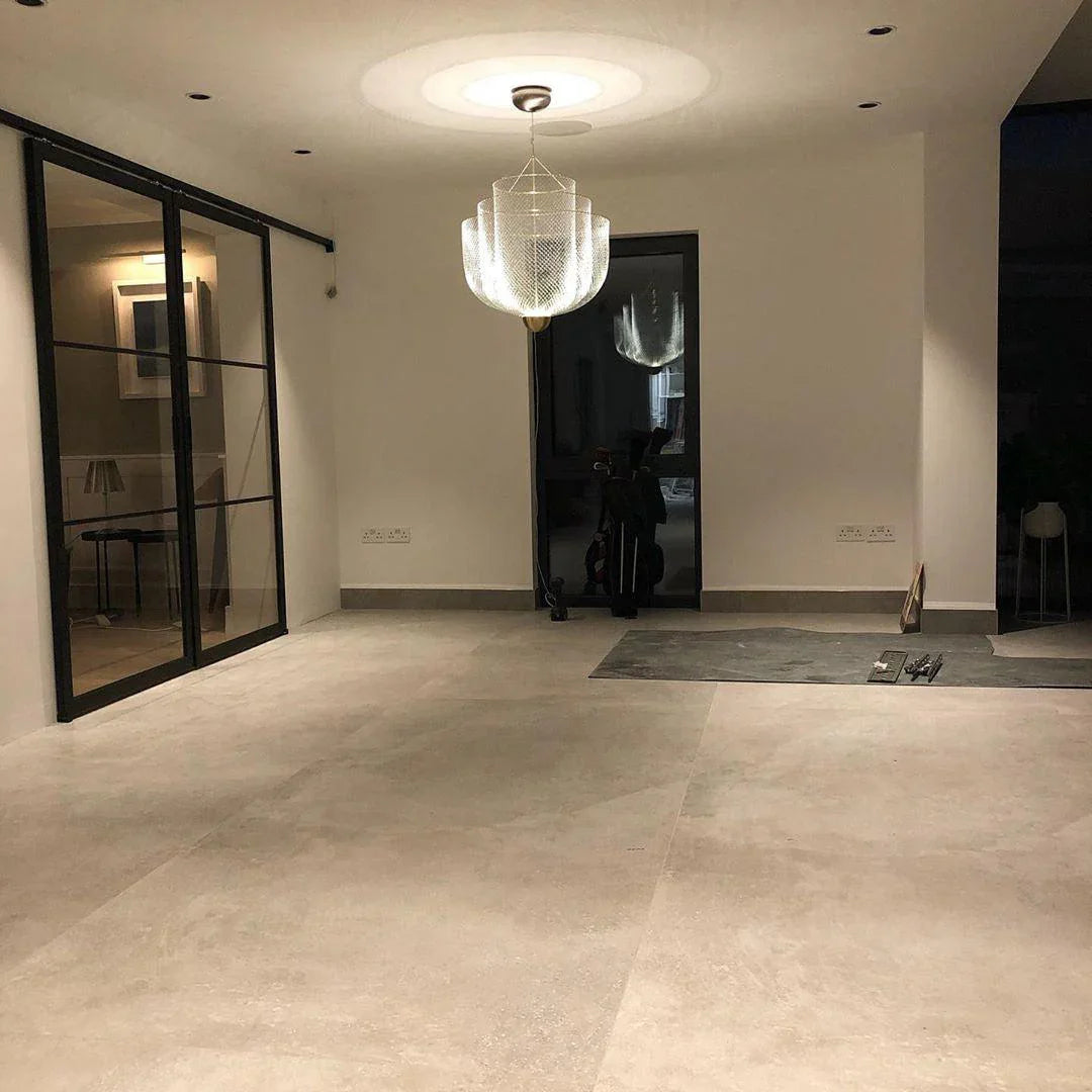 Modern chrome and gold mesh pendant chandelier hanging in minimalist room with large beige tile floor