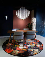 Modern dining room with wooden table, gray chairs, colorful floral round rug, and mesh pendant chandelier
