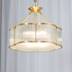 Modern brass pendant chandelier with glass panels from YH Lamps, illuminated against white curtains