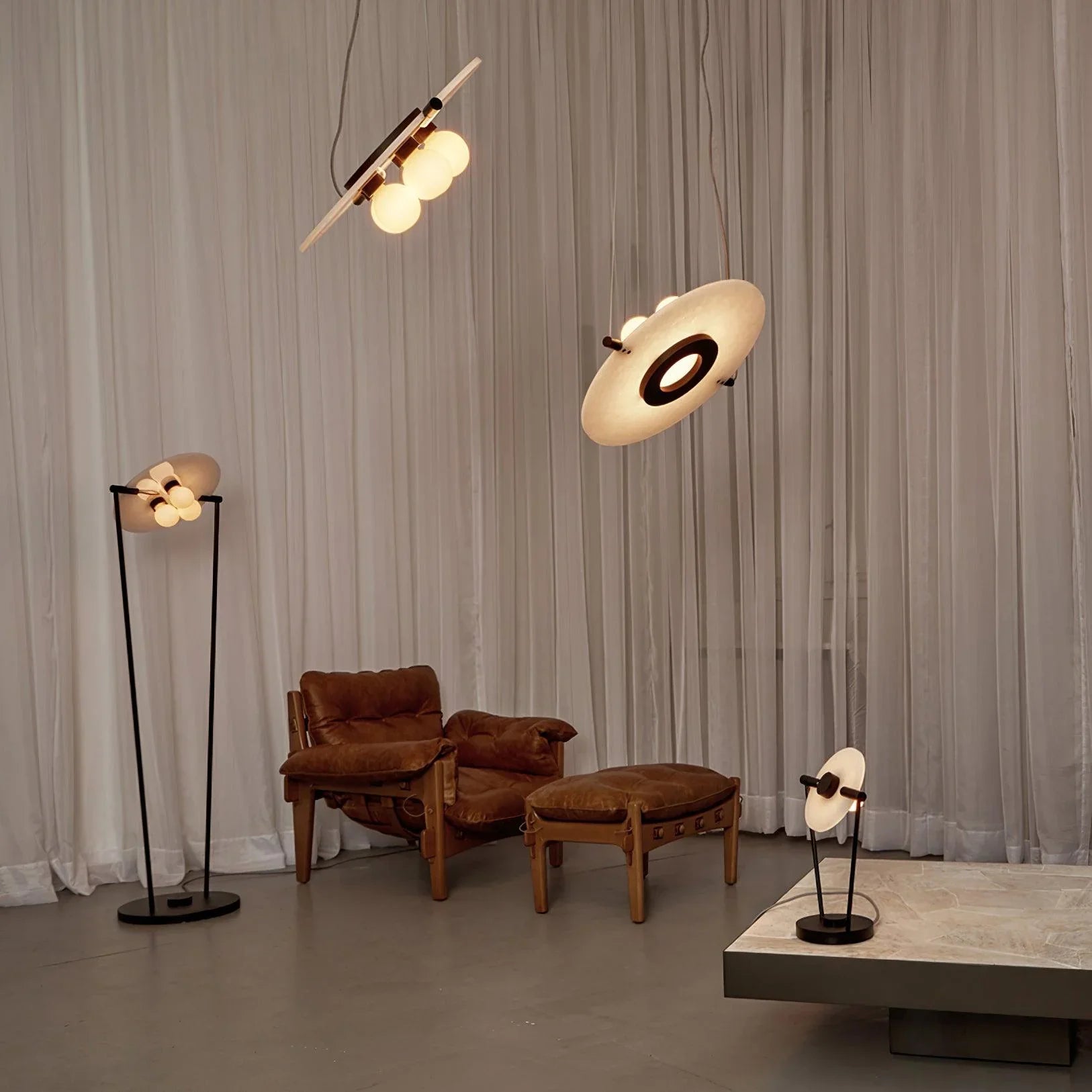Modern living room with brown leather armchair, matching ottoman, and contemporary black and white pendant, floor, and table lamps