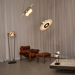 Modern living room with brown leather armchair, matching ottoman, and contemporary black and white pendant, floor, and table lamps