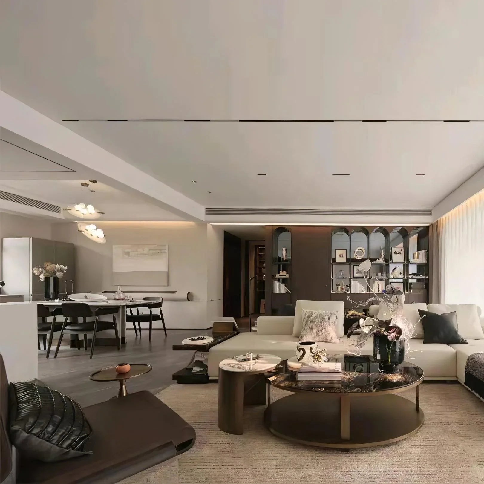 Modern open living and dining room with neutral tones, a white sectional sofa, round coffee tables, and stylish shelving.