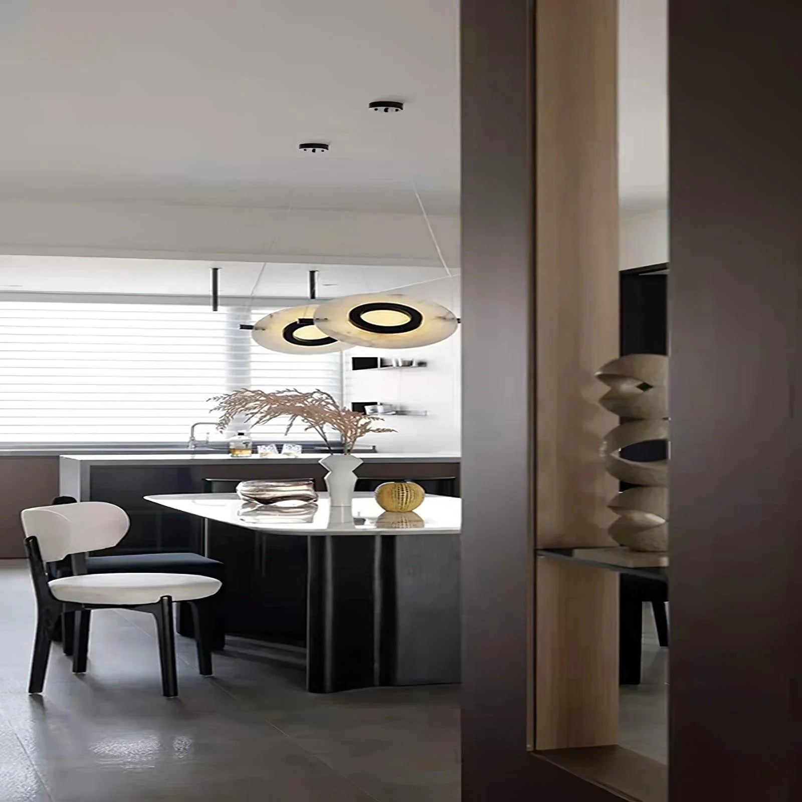 Modern dining area with black and white Magma pendant lamps, white chair, marble table, and decorative vase