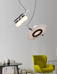 Modern pendant lamps with spherical bulbs and marble-like disc shades above a round black table and lime green armchair