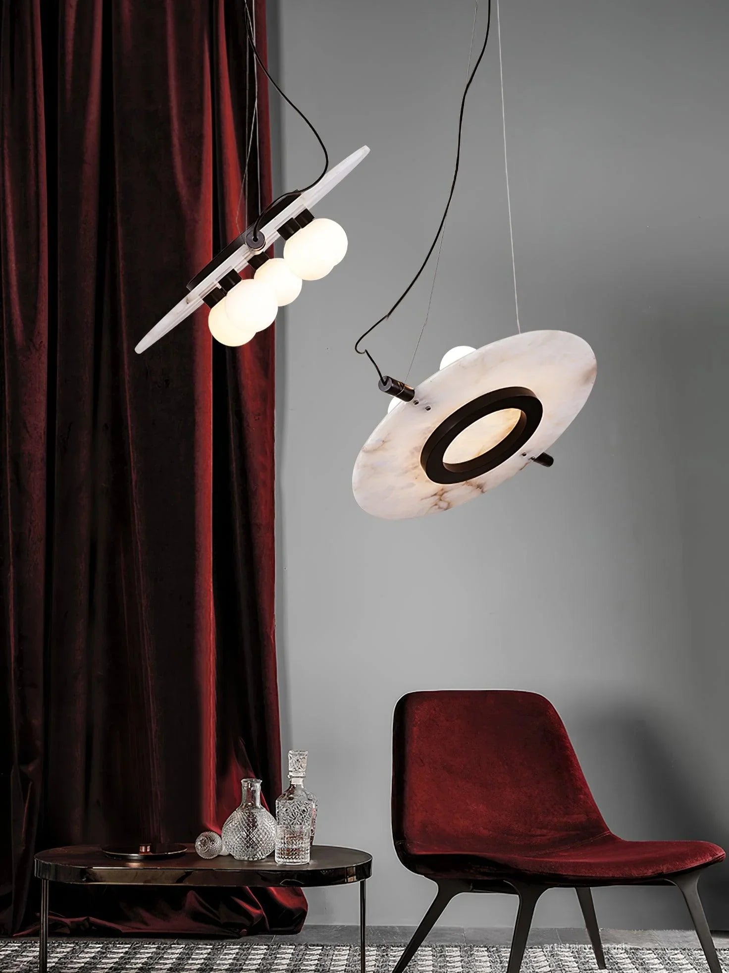 Modern black and white magma pendant lamps with three globe bulbs above a black table and red velvet chair
