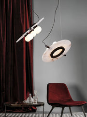 Modern black and white magma pendant lamps with three globe bulbs above a black table and red velvet chair