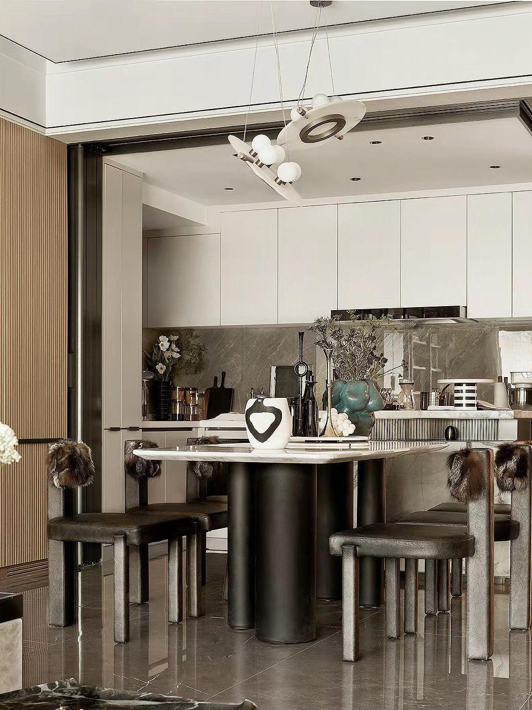 Modern dining room with black and white pendant chandelier, marble table, and chic leather chairs with fur accents