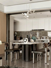 Modern dining room with black and white pendant chandelier, marble table, and chic leather chairs with fur accents