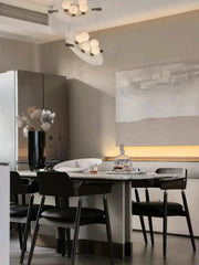 Modern dining room with black chairs, marble table, abstract wall art, and YH Lamps pendant lighting