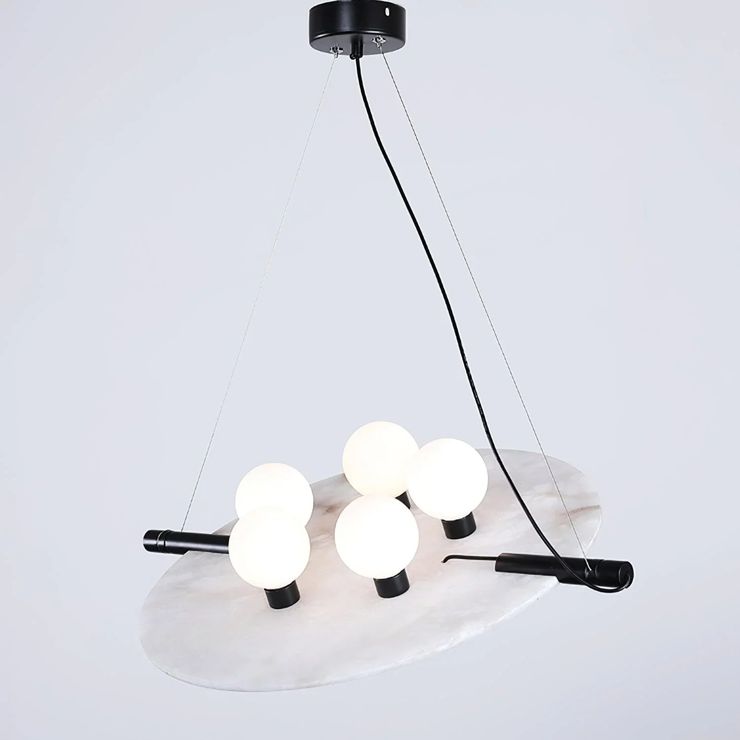 Modern black and white pendant chandelier with five glowing round bulbs on a circular marble plate