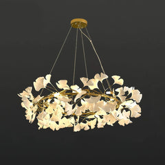 Modern gold and white ginkgo leaf chandelier pendant lamp with warm lighting against dark background