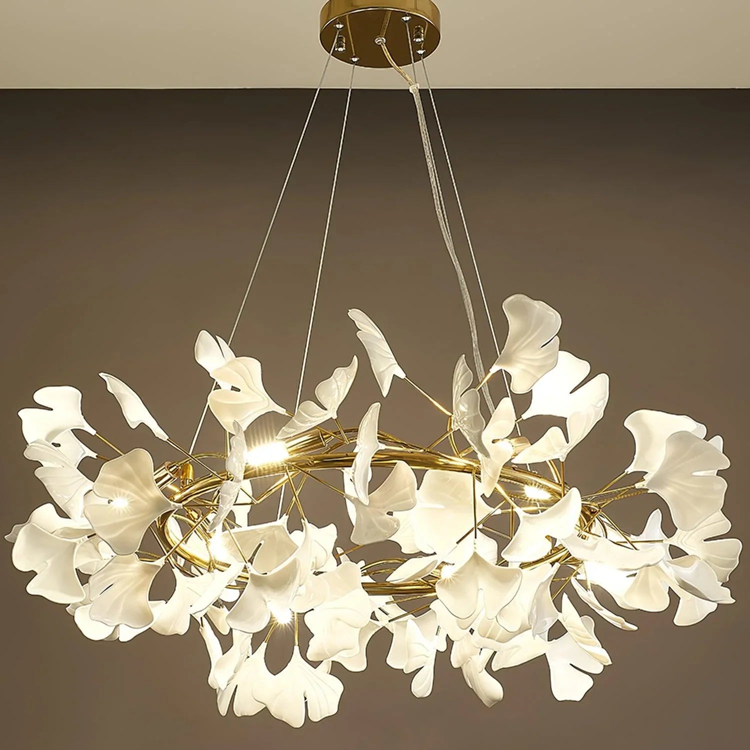 Modern gold chandelier with white gingko leaf-shaped lights suspended from ceiling