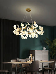 Modern ginkgo leaf gold and white pendant chandelier hanging above a dining table in a stylish room