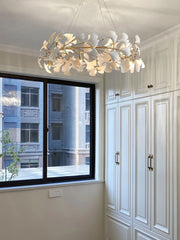 Modern gold and white ginkgo leaf chandelier pendant lamp in elegant room with white cabinets and large window