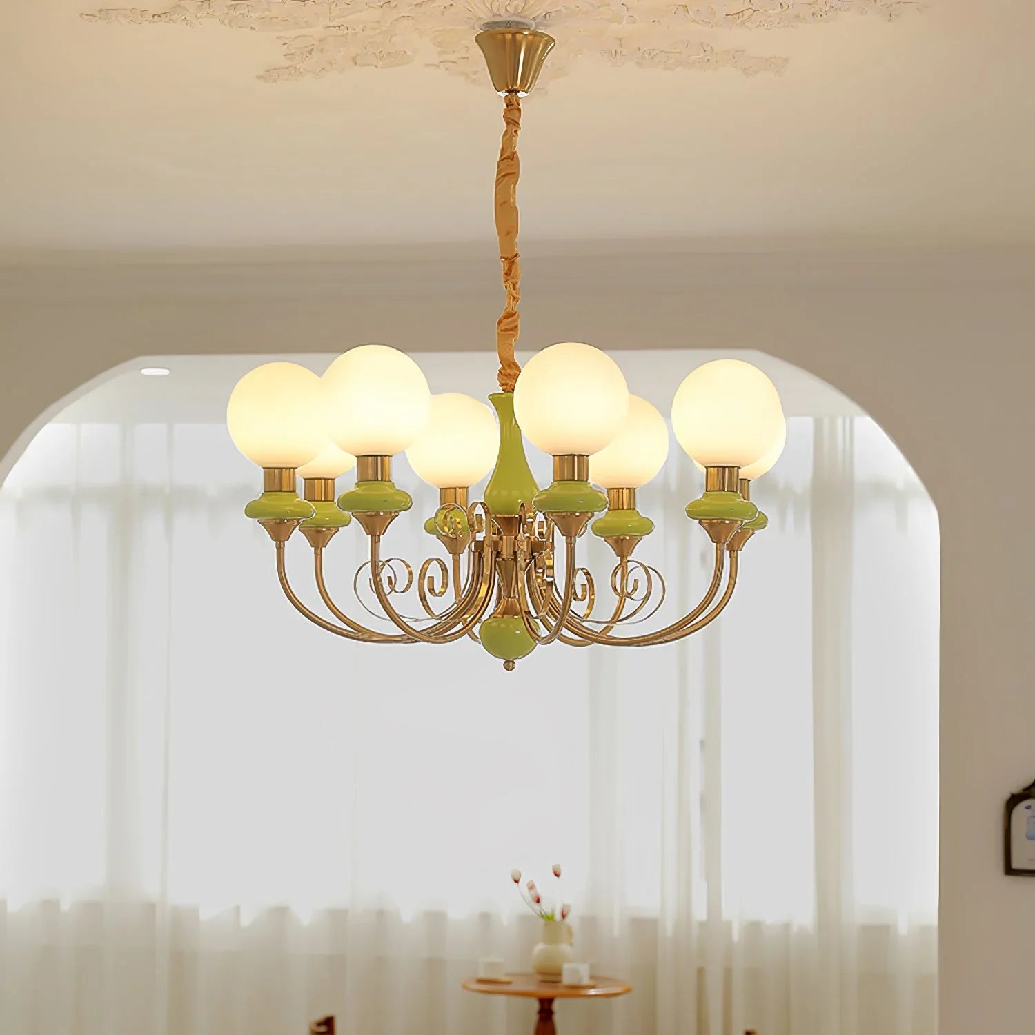 Modern 8-head chandelier with gold and green accents and white globe lampshades in bright room