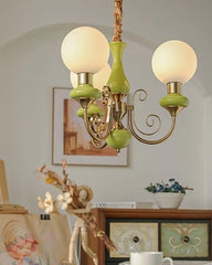 Modern chandelier with three round white glass shades and gold green metal accents hanging in cozy room