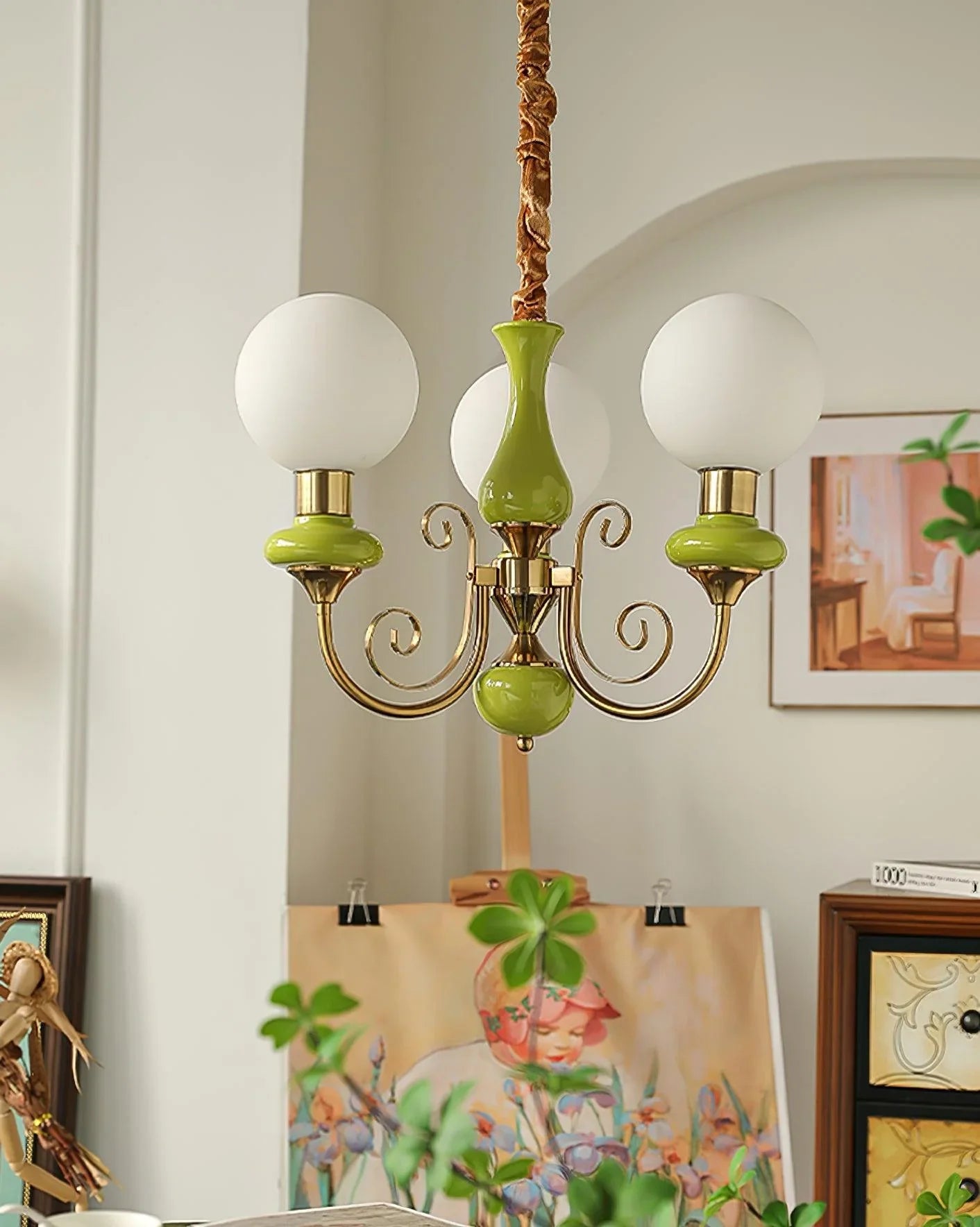 Modern chandelier with three white globe lamps, gold and green accents in cozy home setting