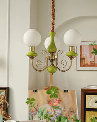 Modern chandelier with three white globe lamps, gold and green accents in cozy home setting