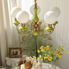 Elegant chandelier with six white globe lights and green gold metal arms over decorated table