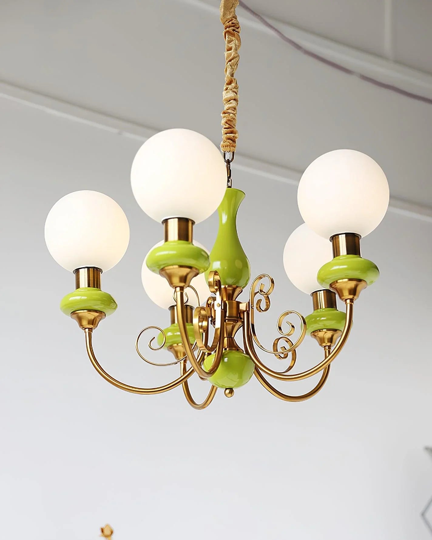 Modern chandelier with five white glass globes, gold metal arms, and green ceramic accents hanging from ceiling