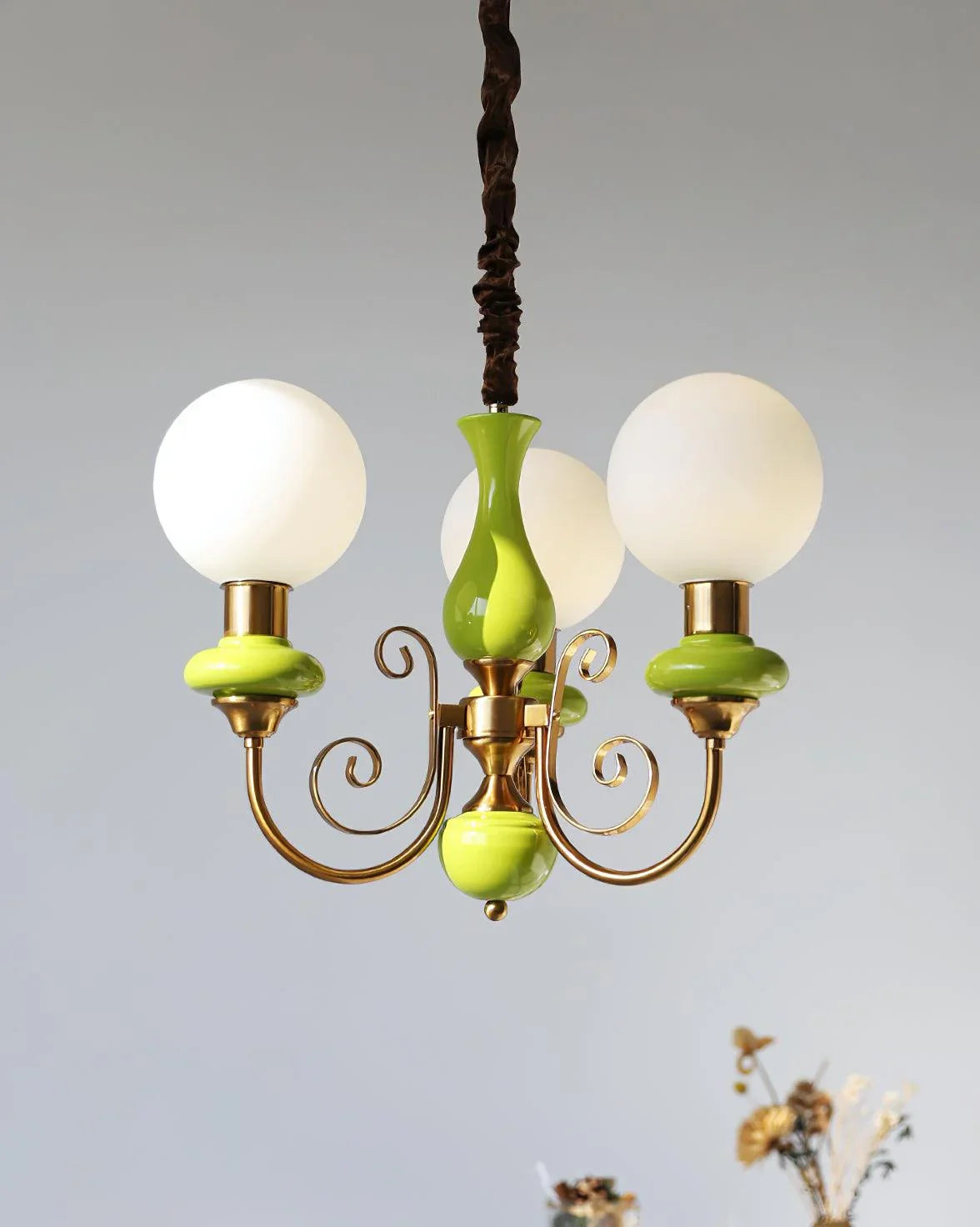 Modern chandelier with three white globe lamps, gold frame, and lime green decorative accents