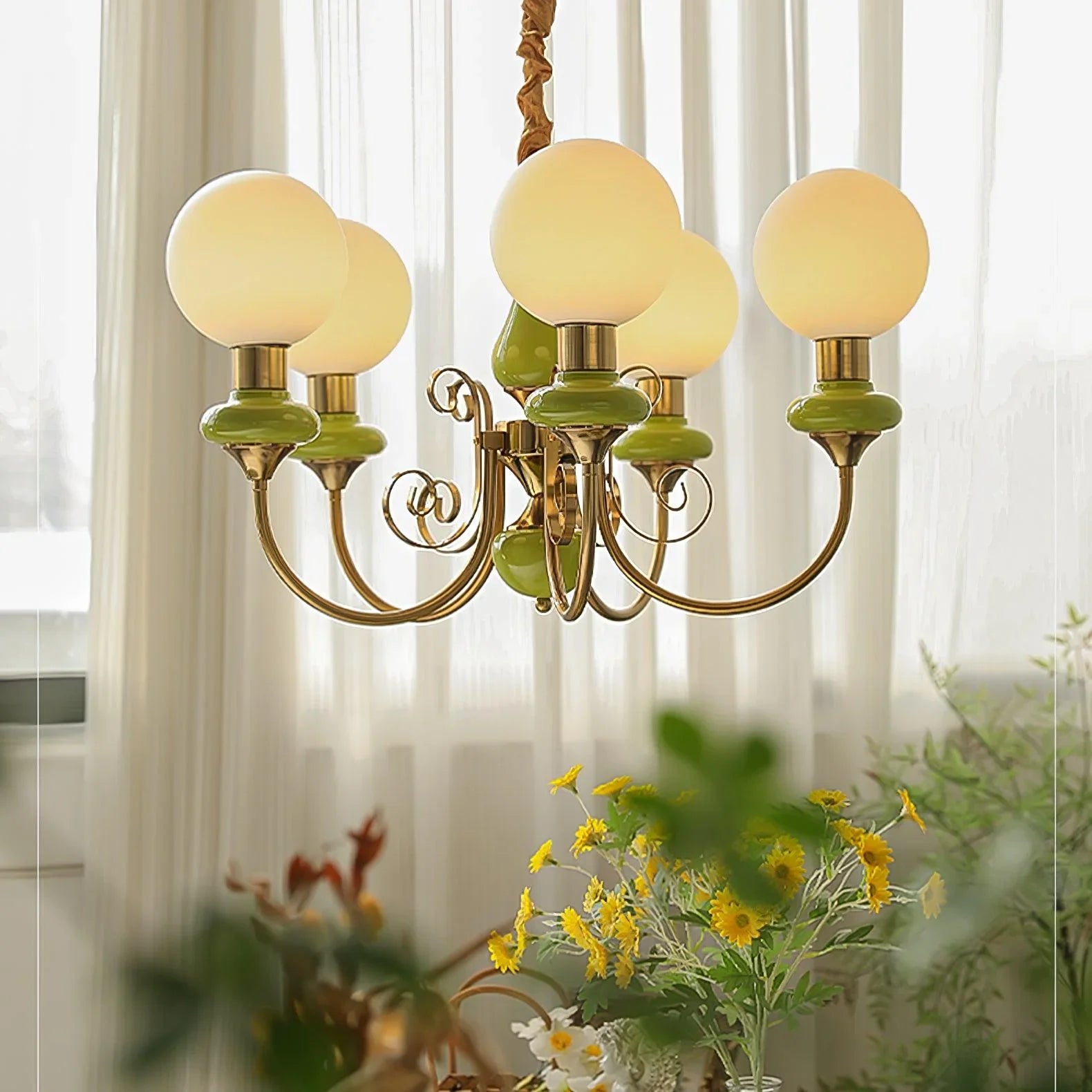 Elegant gold chandelier with five white globe lamps and green ceramic accents in a bright room