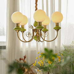 Elegant gold chandelier with five white globe lamps and green ceramic accents in a bright room