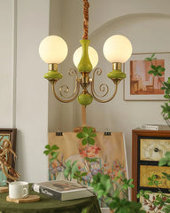 Modern 3-head pendant chandelier with gold and green accents hanging in cozy room with art, books, plants