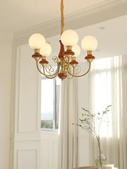 Elegant six-light chandelier with round white glass globes and gold-green accents in bright modern room