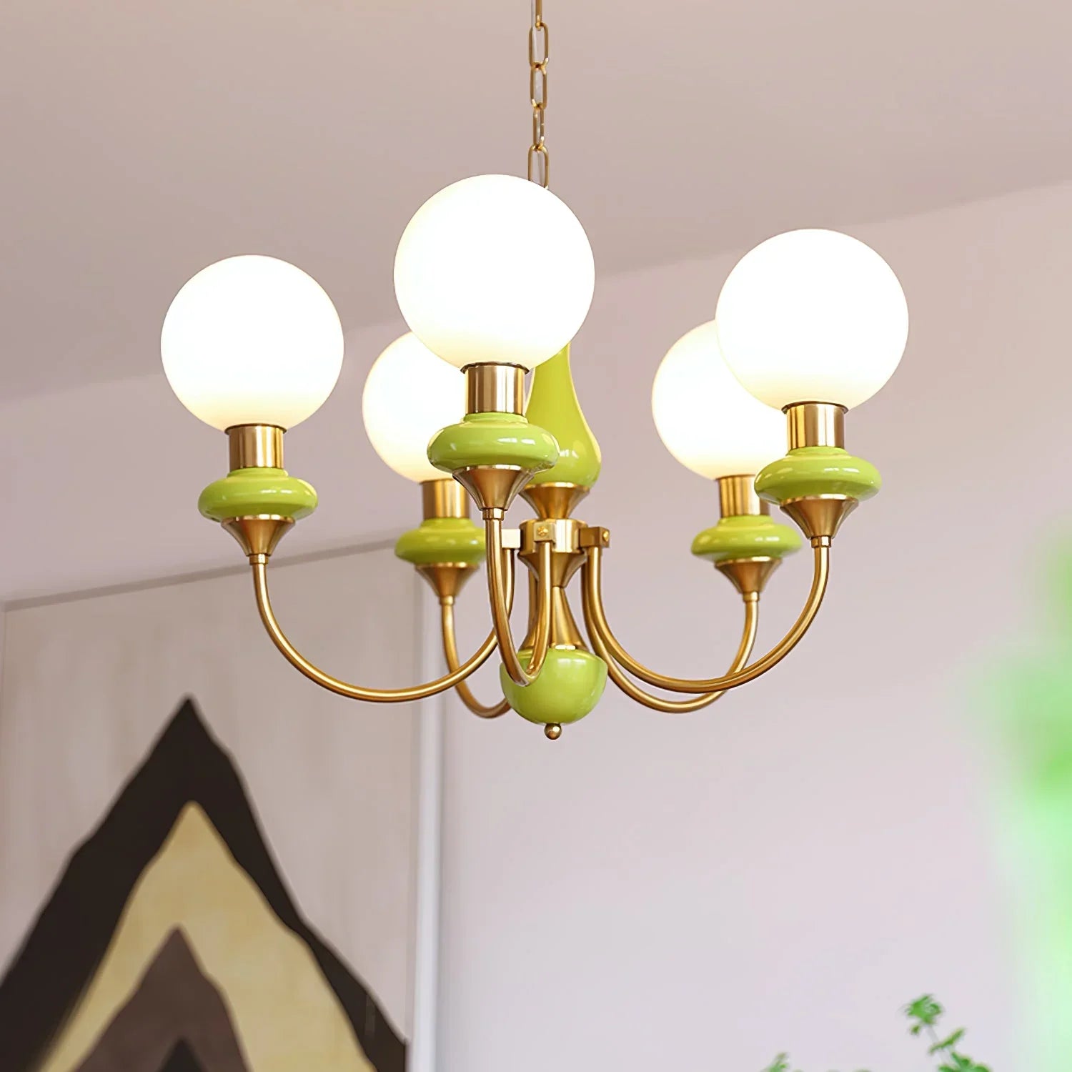 Modern gold and green chandelier with five round white glass bulbs in stylish home interior