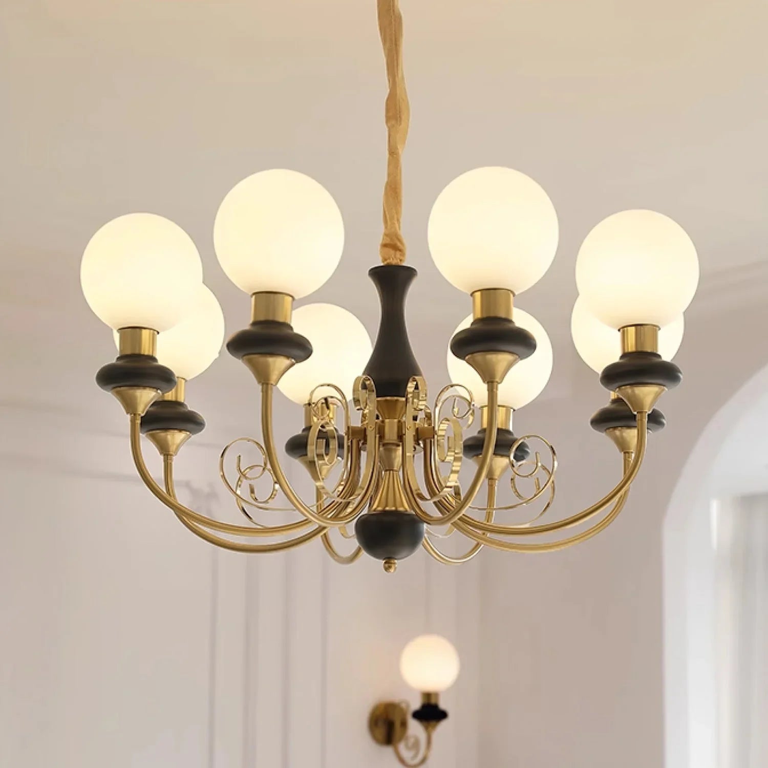 Modern gold and black chandelier with nine white globe lights hanging in a bright room