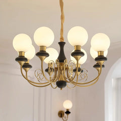 Modern gold and black chandelier with nine white globe lights hanging in a bright room