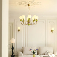 Elegant living room with gold and green multi-globe chandelier, beige sofa, wall sconces, and decorative molding