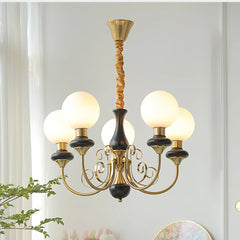Modern chandelier with six frosted glass globes, gold and black metal arms, hanging in a bright room