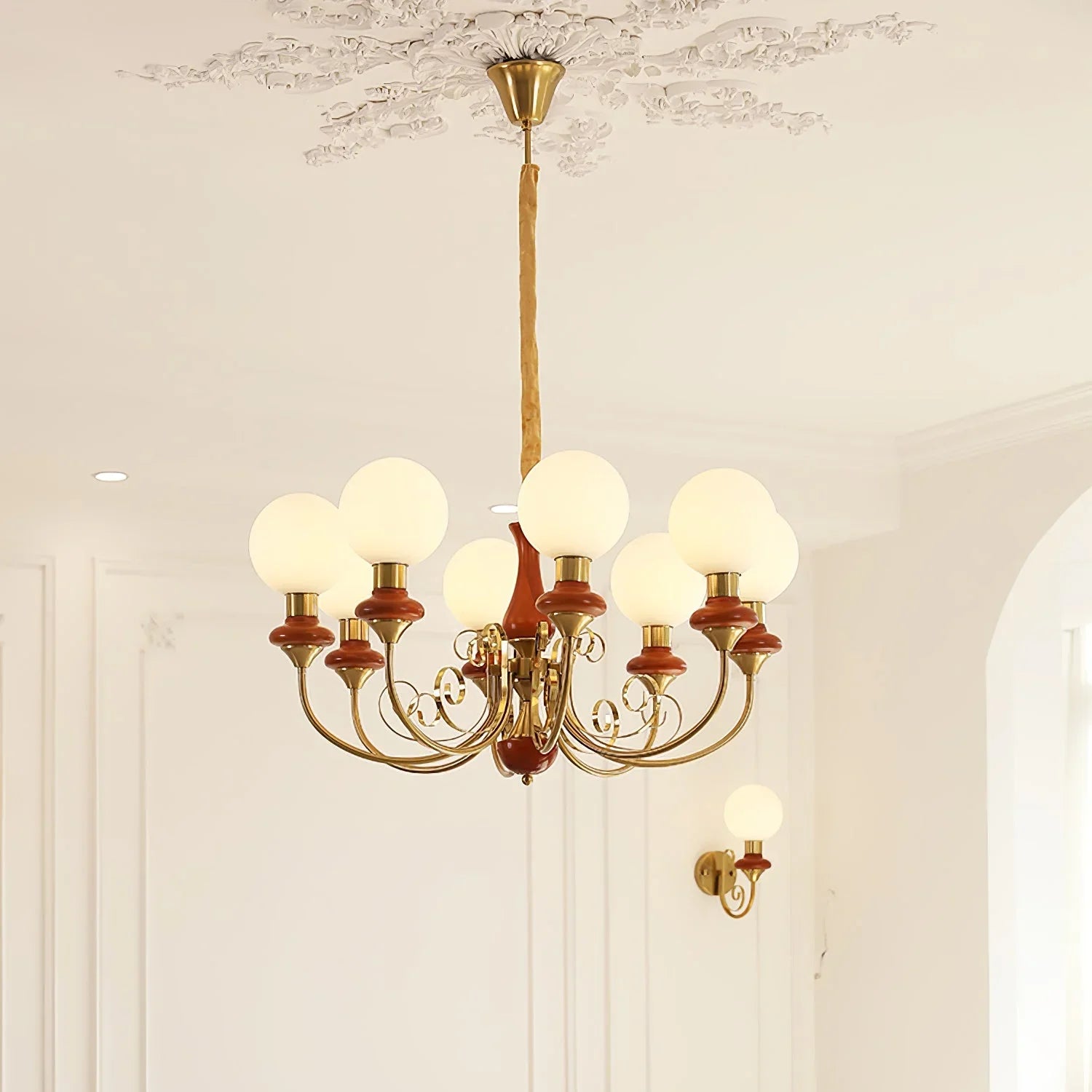 Modern 3-head chandelier with gold and brown metal arms and white globe lamps in elegant room