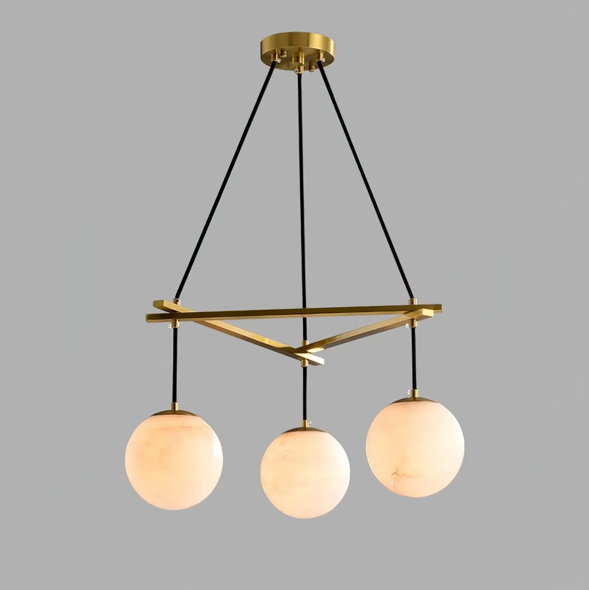 Modern three-light chandelier with brass frame and white alabaster spherical shades suspended by black cords