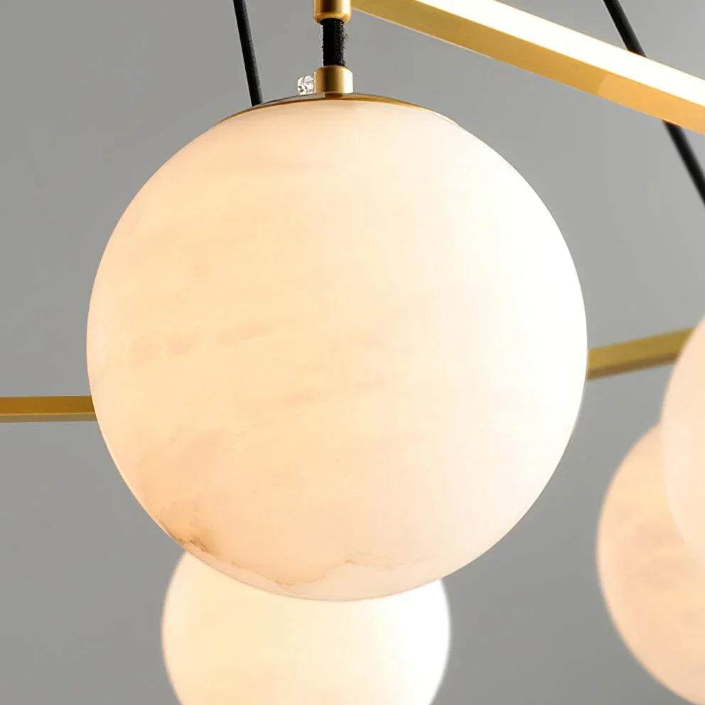 Modern chandelier with three alabaster globe lamps and brass fixtures against a gray background