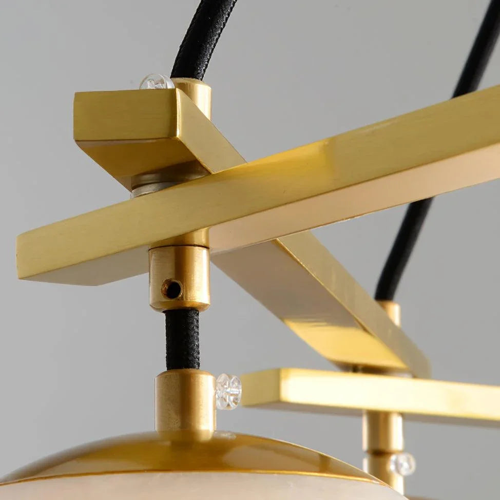 Close-up of brass modern chandelier frame with black cords and alabaster lamp shade detail